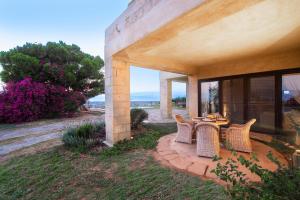 a patio with wicker chairs and a table on a house at Majestique Villa Aegina in Egina