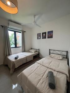 a bedroom with two beds and a window at Duchess Home Taman Colonial in Raub
