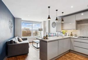 a kitchen with white cabinets and a couch in a room at 'Bright Gem by the Sea' Premium Central 2 bedroom flat in Brighton & Hove