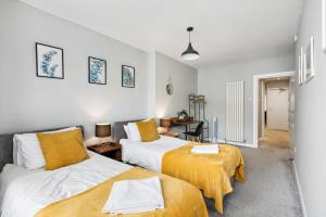 a bedroom with two beds with yellow sheets at 'Bright Gem by the Sea' Premium Central 2 bedroom flat in Brighton & Hove +37 photos