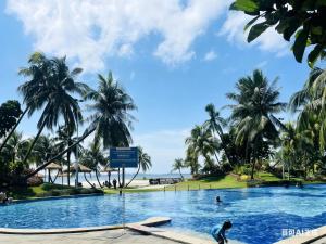 a pool with palm trees and the ocean in the background at Best Hotel in Johor Bahru