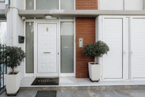 a white door on a brick building with two potted plants at Zoe's Luxury Living in Volos