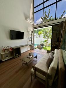 a living room with a couch and a tv at Gauri Vasanta Villa with Private Pool Yogyakarta in Yogyakarta