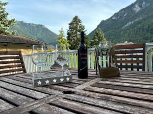 a bottle of wine and two wine glasses on a wooden table at Garden Lodge Minou in Hirschwang