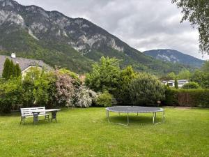 a table and bench in a yard with mountains in the background at Garden Lodge Minou in Hirschwang