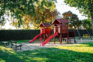 a playground with a red slide and a bench at Levendula Hotel in Algyő