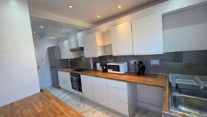 a kitchen with white cabinets and a microwave on a counter at Nice Living Serviced Accommodations 15 in Allesley +12 photos
