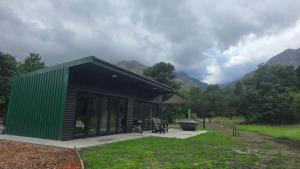 a green and black building with mountains in the background at Tranquility - Cabin nestled in the mountains in Worcester