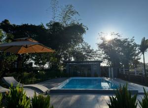 a swimming pool with an umbrella and the sun at Tuyo Homestay in Ban Pang Kiang