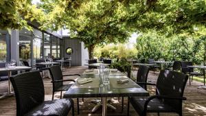 a dining room with tables and chairs and trees at Hostellerie Saint Germain in Saint-Germain-lès-Arlay
