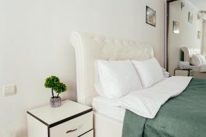 a bedroom with a white bed with a plant on a night stand at Central Park Apartment 4 Guests in Chişinău