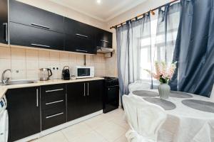 a kitchen with black cabinets and a table with a vase of flowers at Central Park Apartment 4 Guests in Chişinău