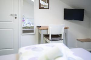 a room with a desk with a television and a white chair at Hotel Eintracht in Fellbach
