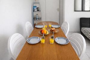 a wooden table with plates of food and glasses of orange juice at Maisonnette cosy avec jardin - proche port et plage in Dives-sur-Mer