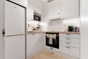 a white kitchen with white cabinets and appliances at Funky City Apartment By Lapland Host in Rovaniemi