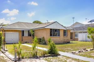 a brick house with a garage in a yard at Barefoot Bungalow in Nelson Bay