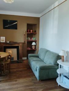 a living room with a green couch and a table at Poterie d'Art in Embrun