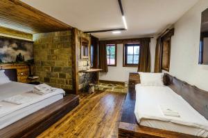 two beds in a room with wooden floors and windows at Разбойна in Zheravna