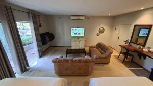 a living room with couches and a flat screen tv at Butlers Crown in Klerksdorp