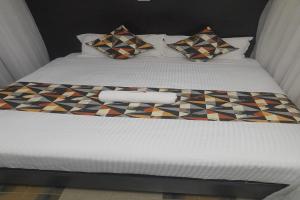 a bed with a checkered blanket and pillows on it at Ohm Village Inn in Kitui