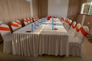 a long table with orange and white chairs around it at Ohm Village Inn in Kitui