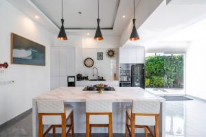 a kitchen with a large white island with wooden chairs at Luxury 5BR Villa with Rooftop BBQ Pool 500M to Beach in Canggu