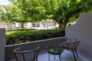 two chairs and a table on a patio with trees at Eliros Mare Beachfront Poem Hotel in Georgioupolis