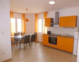 a kitchen with orange cabinets and a table and chairs at Apartmani Kvesic - Azzurro in Šilo