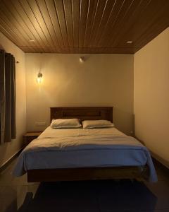 a bedroom with a large bed with a wooden ceiling at Pebbles in Thirunelli