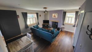 a living room with a blue couch and a table at Gardeners Cottage Apartment in Tyberton