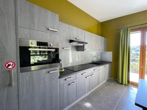 a kitchen with gray cabinets and a large window at Gîtes Le Bouzet in Salavas