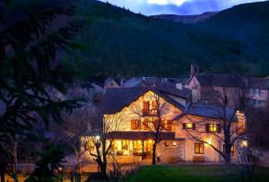 a large house with lights on it at night at Hotel Restaurant de charme La Lozerette - Proche Florac in Cocurès