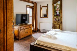 a bedroom with a bed and a flat screen tv at Разбойна in Zheravna