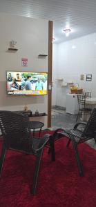 a room with two chairs and a tv on the wall at Kitnet próximo ao shopping in Campo Grande