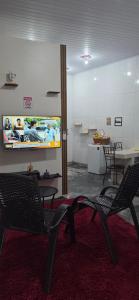 a room with chairs and a tv on the wall at Kitnet próximo ao shopping in Campo Grande