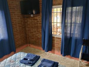 a room with blue curtains and a bed and a window at Cabaña María Lourdes in Maipú