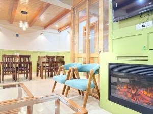 a room with a fireplace and chairs and a table at Private Villa Alpine Escape 6BHK in Manāli