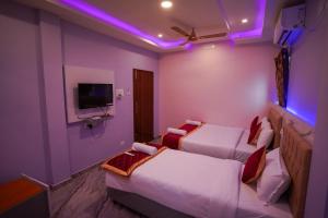 a hotel room with two beds and a tv at P V Grand in Dindigul