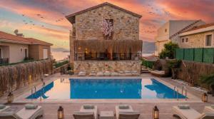 a villa with a swimming pool in front of a building at Stone House Foça Otel in Yenifoça