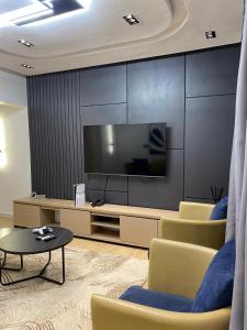 a living room with a flat screen tv and chairs at Greyfield Apartment 1 in Benin City +6 photos