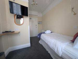 a hotel room with a bed and a flat screen tv at Del Mar in Llandudno