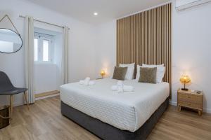 a bedroom with a large white bed with two lamps at Achadinha Sunset House - São Miguel, Açores in Achadinha