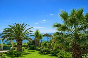 a garden with palm trees and the ocean in the background at THERETRA KIOTARI VILLAS in Gennadi