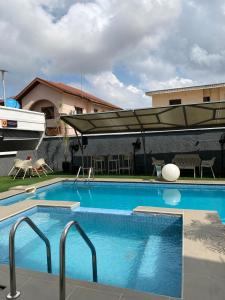 a swimming pool with an umbrella and a boat at Greyfield Apartment 1 in Benin City