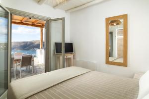 a bedroom with a bed and a mirror and a table at West Side Pool House by Hostandros in Gavrio