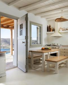 a kitchen with a table and a bench and a window at West Side Pool House by Hostandros in Gavrio