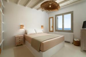 a white bedroom with a bed and a window at West Side Pool House by Hostandros in Gavrio +33 photos