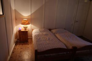 two beds in a room with a lamp on a table at Ferme en pleine nature in Boudevilliers