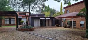 a house with an umbrella and a brick building at Butlers Crown in Klerksdorp