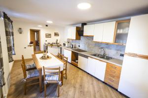 a kitchen with white cabinets and a table and chairs at Appartamenti dei Maerins in Pozza di Fassa